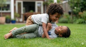 image 2 - Two children playfully wrestling on a soft grass field, smiling and showing healthy social interaction
