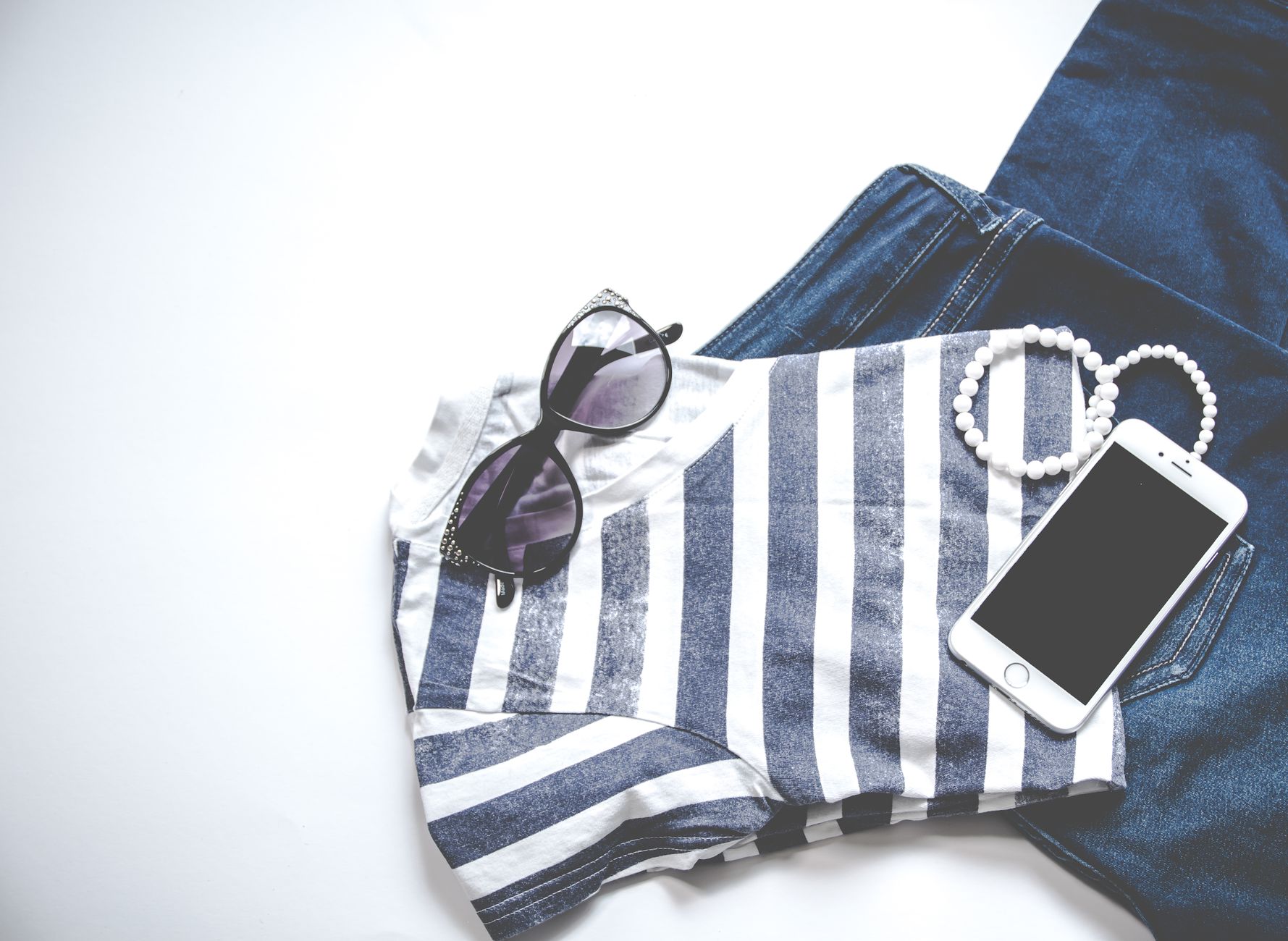 Flat-lay of essential capsule wardrobe items like shirts, jeans, and sneakers.