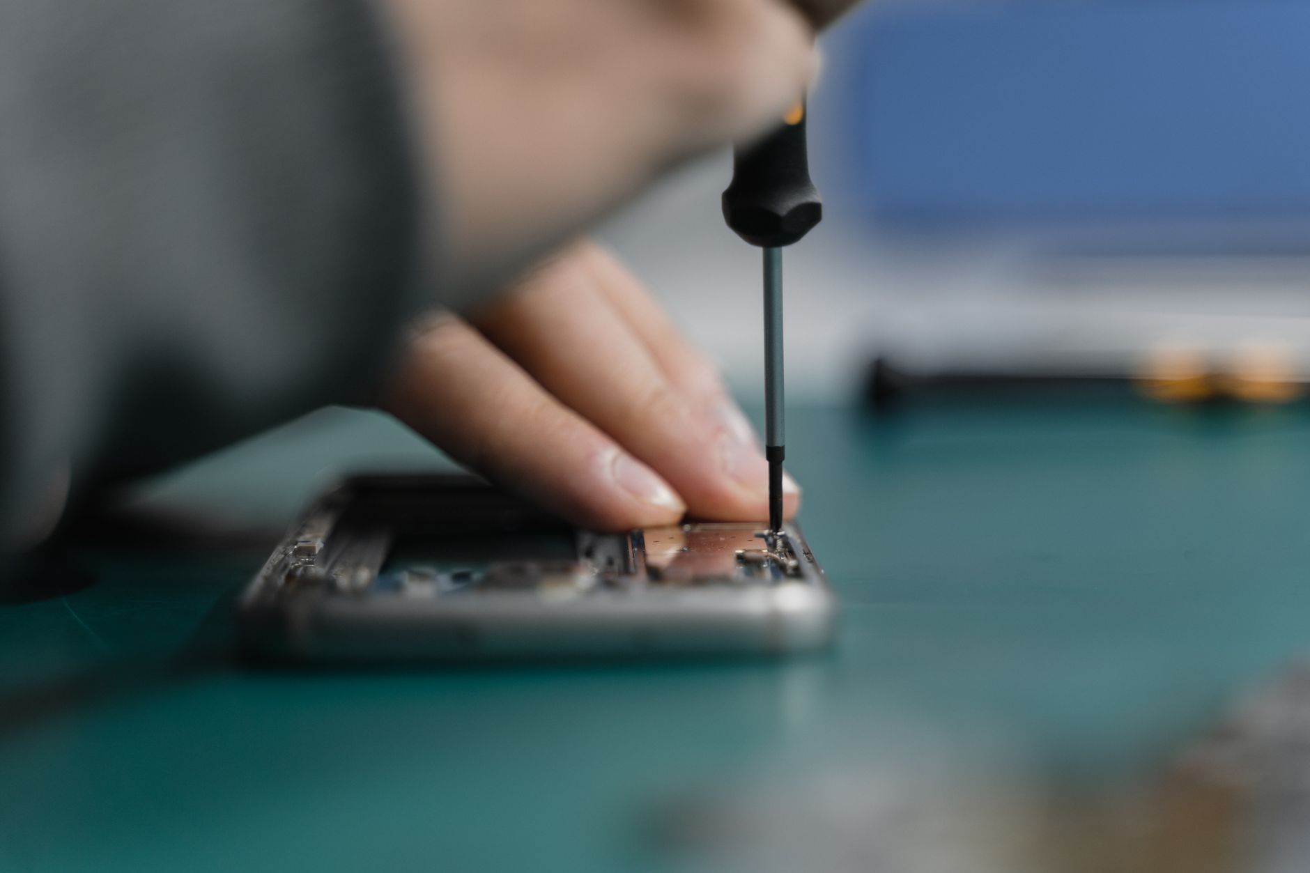 Close-up of hands repairing a smartphone with a precision screwdriver.