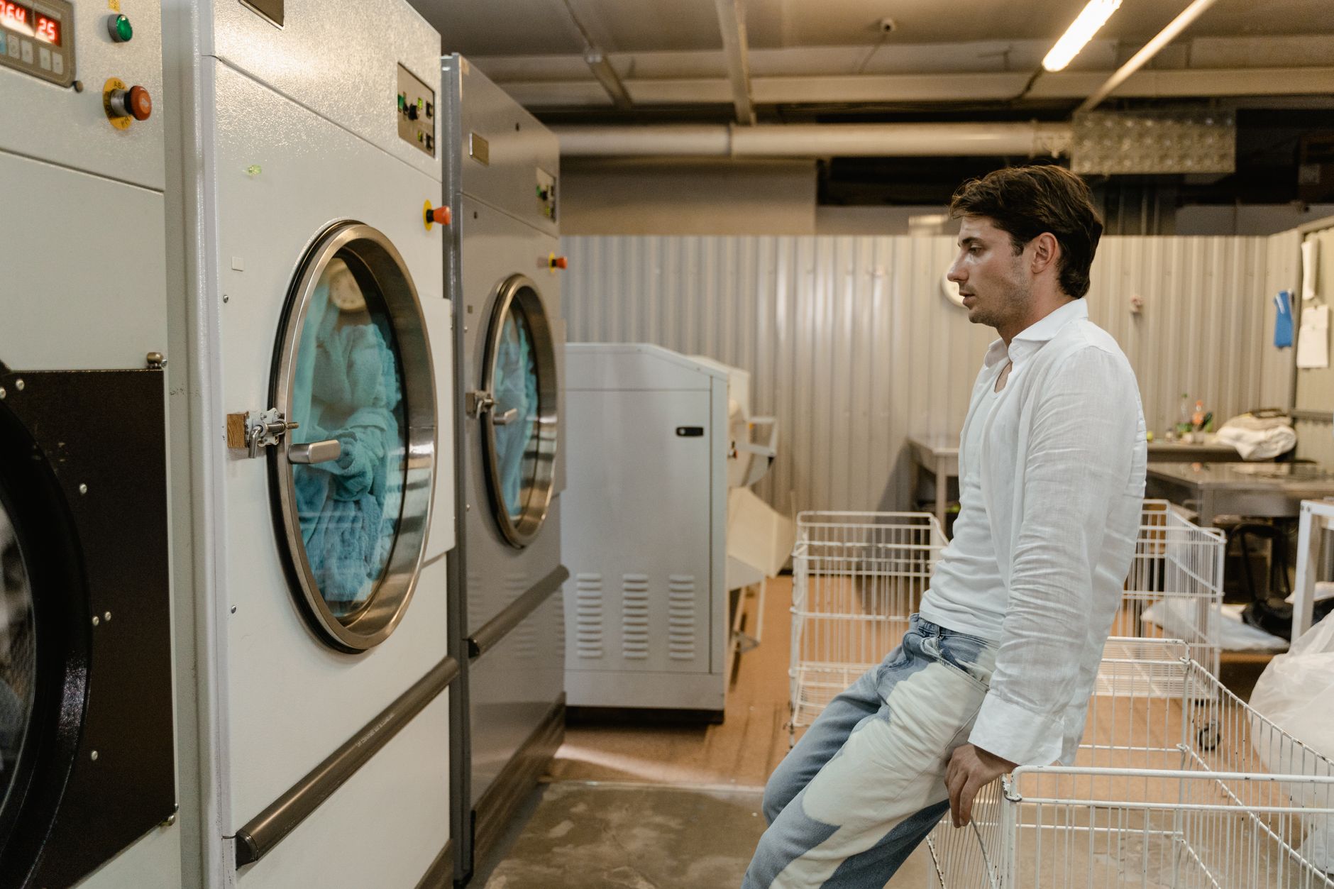 A person inspecting the back of a washing machine to diagnose a mechanical issue.