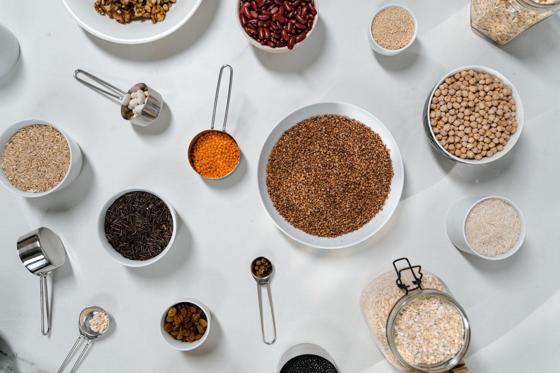 A variety of plant-based pantry staples in glass jars on a kitchen counter.