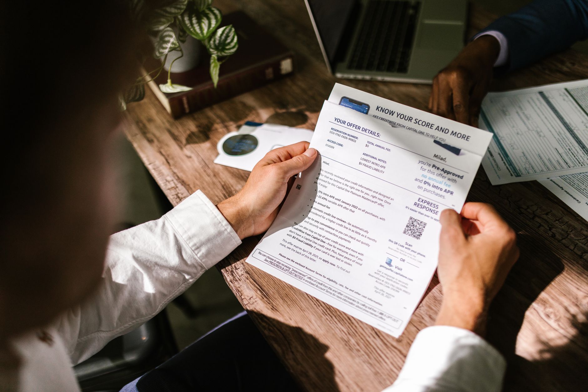 A person reviewing bank statements at a kitchen table.