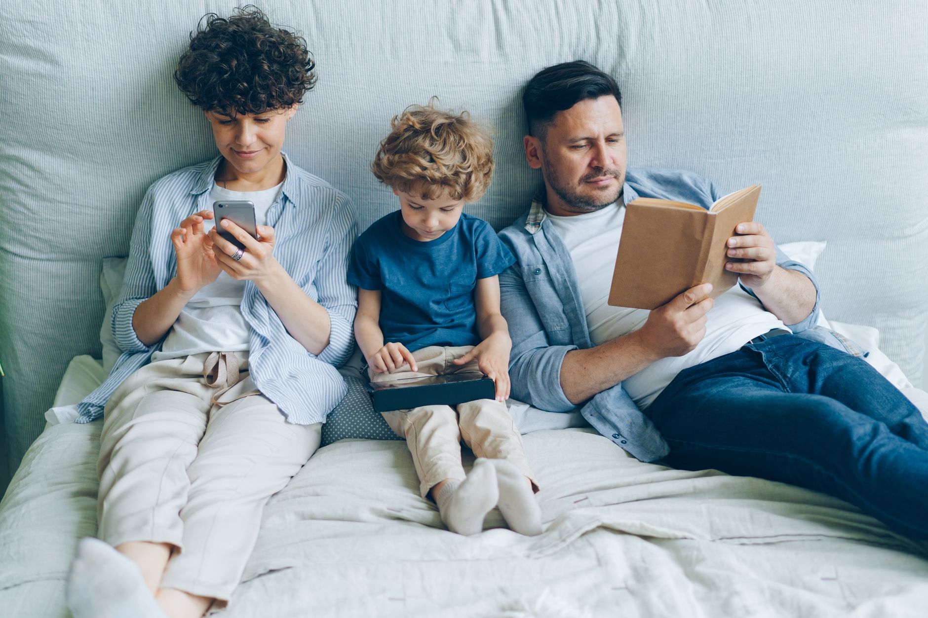 Parent relaxing with a physical book to escape digital noise.