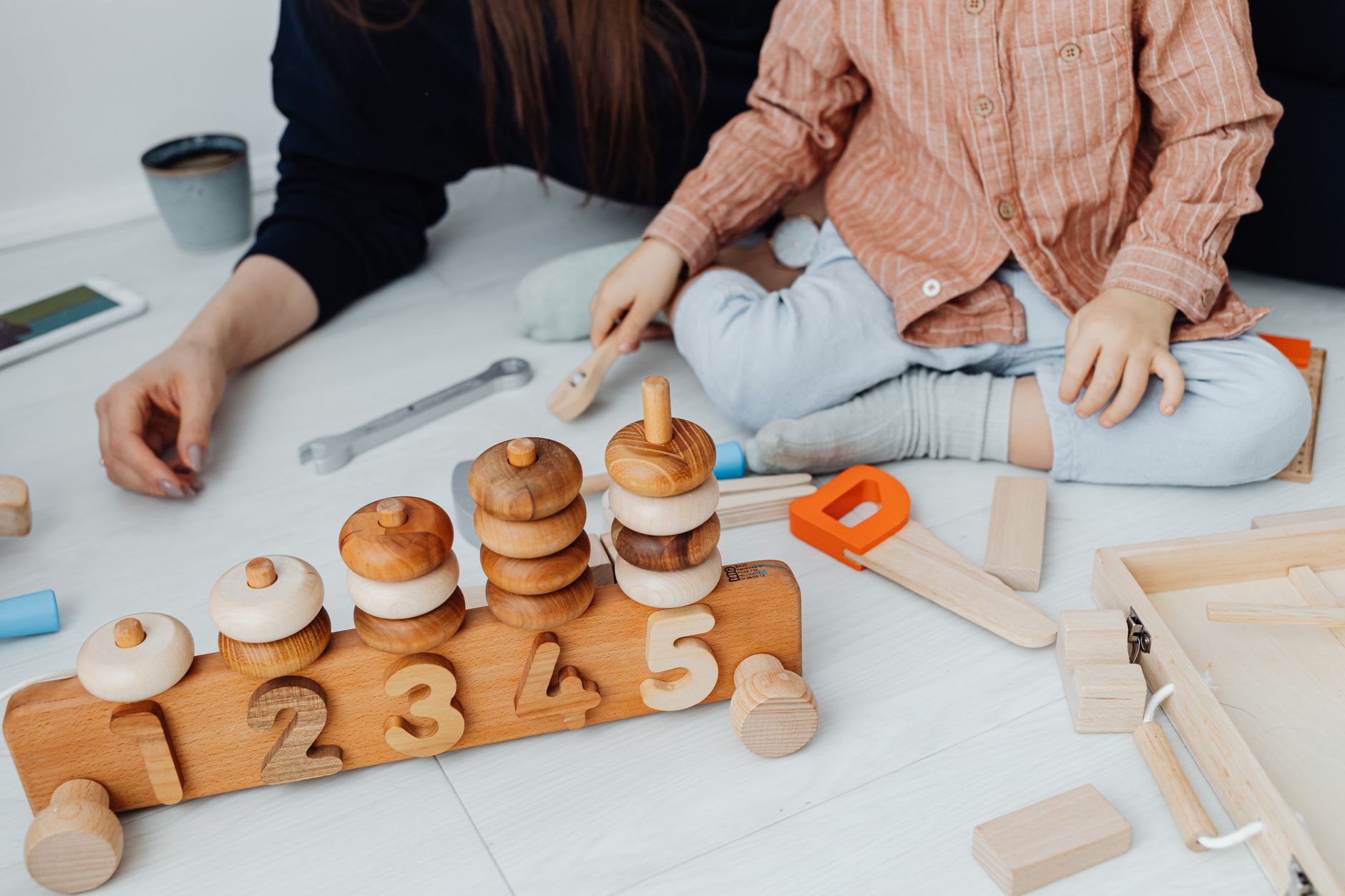 A parent and child exploring with loose parts, highlighting parent-supported free play.