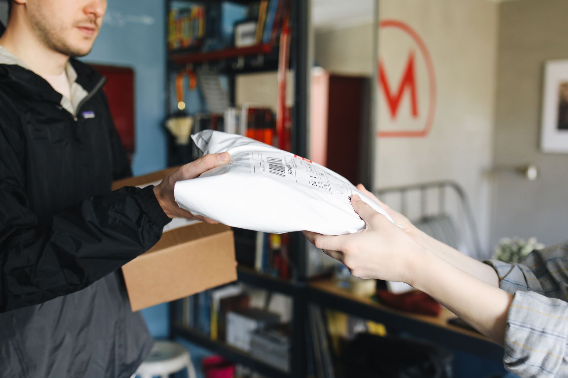 Two people exchanging a bag of goods in a neighborhood setting.