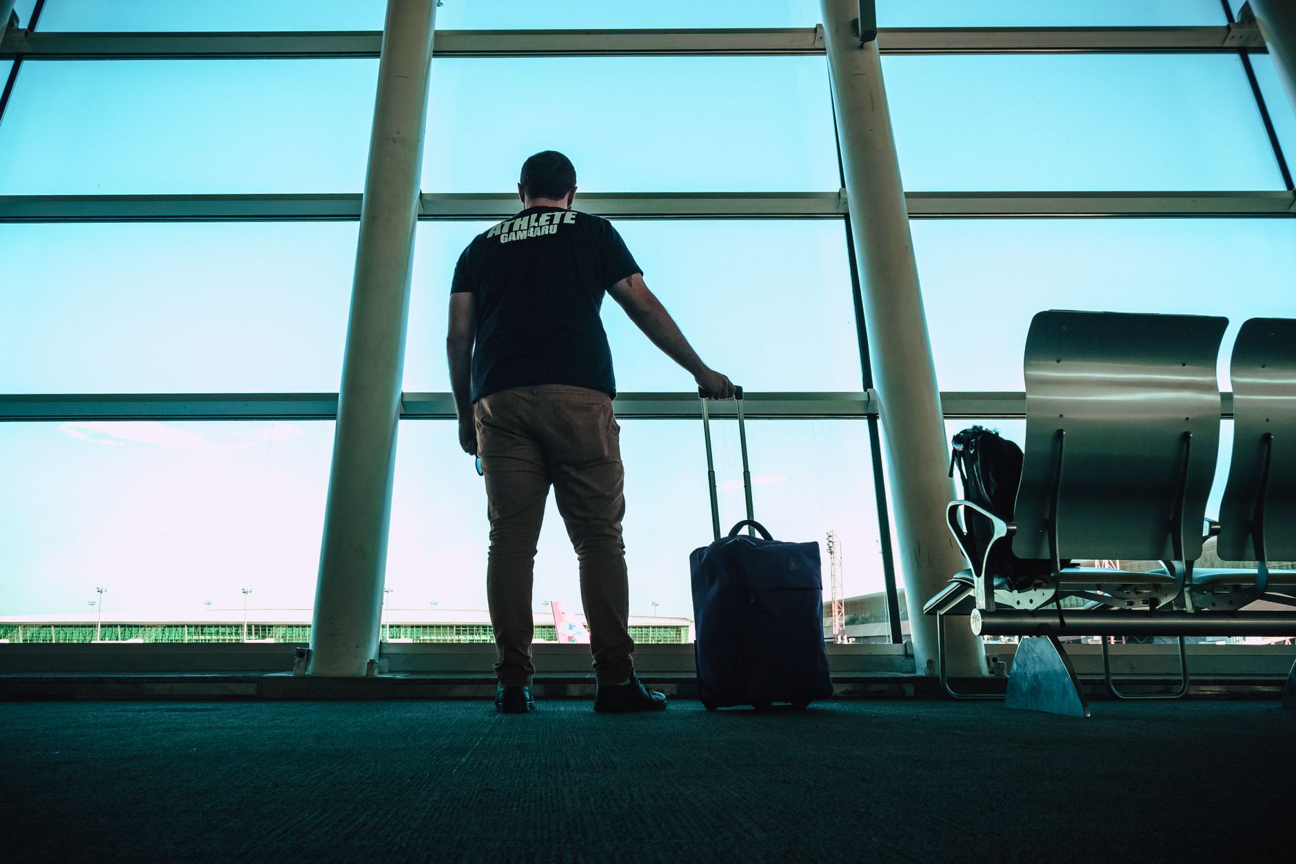 Traveler with a dog and luggage at an airport gate.