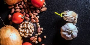 A vibrant spread of fresh plant-based foods including vegetables, legumes, and grains on a wooden table.