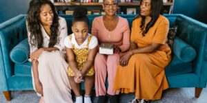 A multi-generational family sitting together in a living room, engaged in a positive conversation.