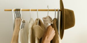 A minimalist, organized closet featuring a curated selection of neutral-colored clothing.