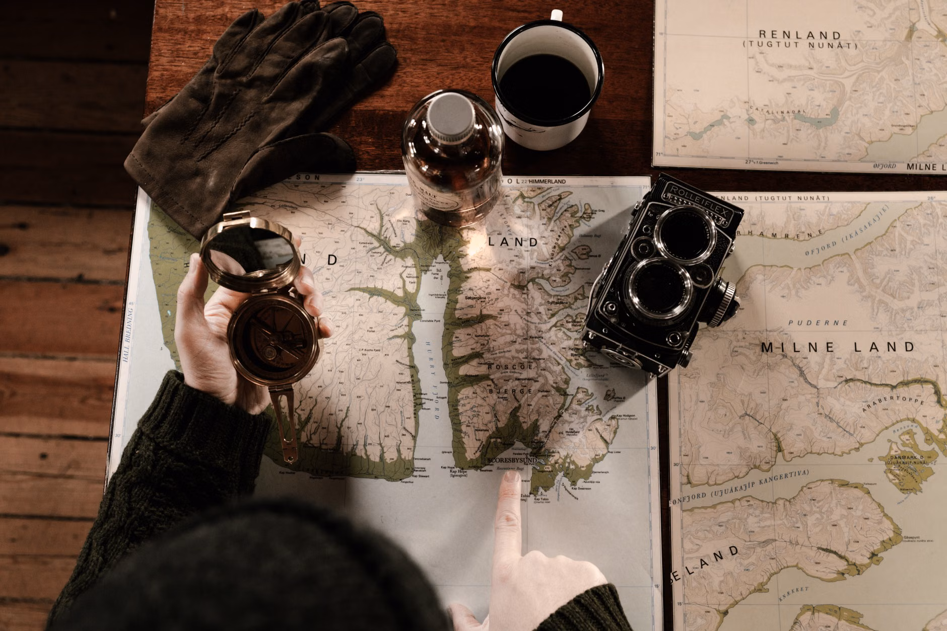 Hands comparing an old paper map with a digital map to find historical locations.