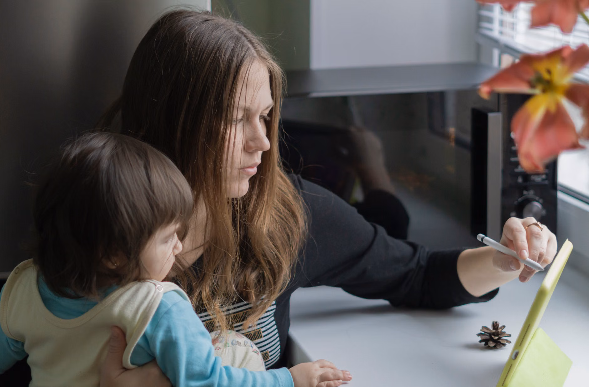Parent and child using a tablet to track chores in a kitchen.
