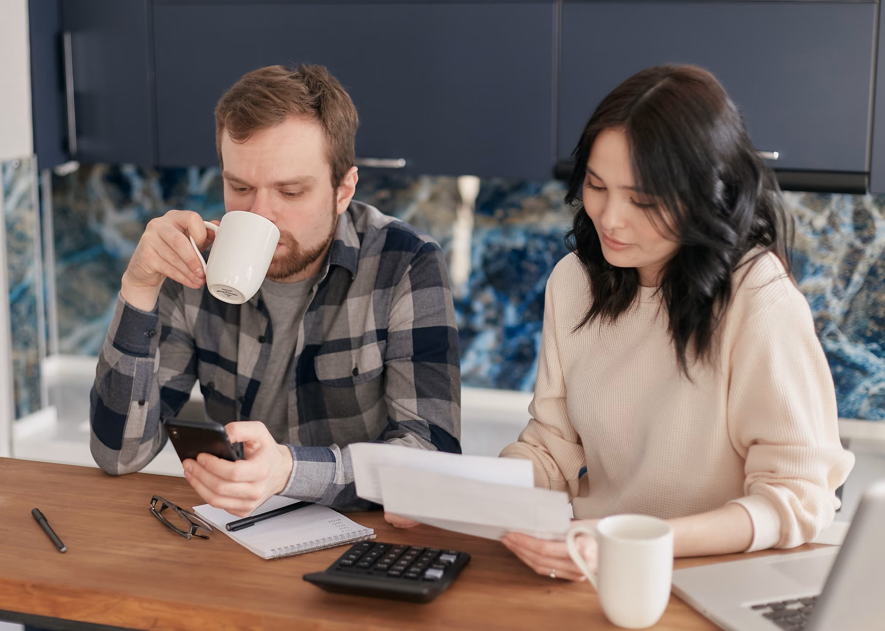 A young parent reviewing home utility bills and finding savings.