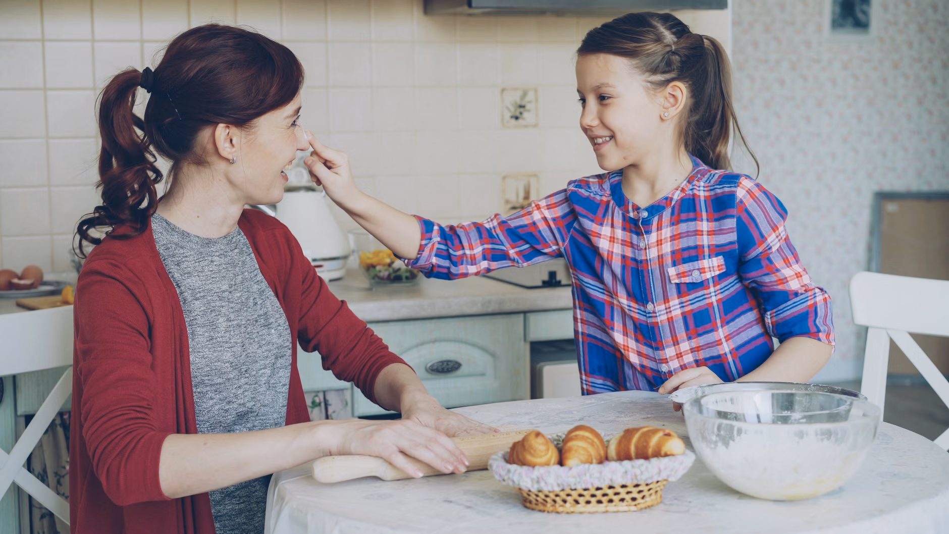 A parent and child baking together in a relaxed home kitchen environment.