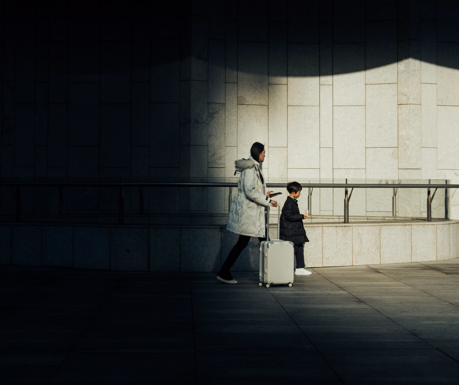 A parent and child waiting for public transit while checking a navigation app.
