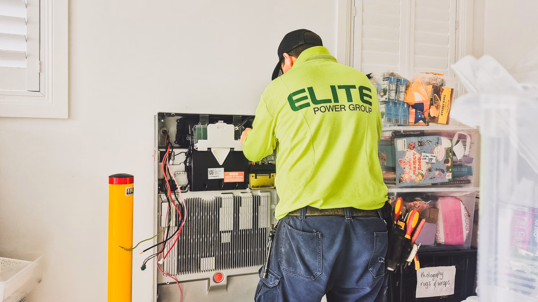 Technician installing a home energy storage battery unit in a garage.
