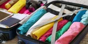 A neatly organized carry-on suitcase containing clothing and accessories.