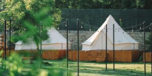 A scenic glamping site featuring a luxury tent and string lights in a peaceful forest setting.