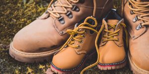A durable family travel backpack and children's shoes on a wooden floor.