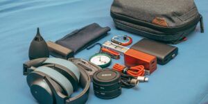 Flat lay of essential travel tech and universal adapters on a wooden table.