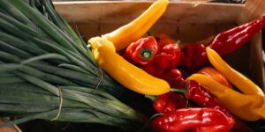 A wooden crate of fresh seasonal vegetables on a rustic kitchen table.