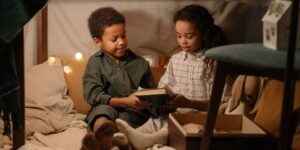 Two children working together to build a cardboard fort in a living room.