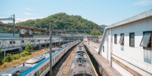 A modern train pulling into a scenic mountain station, representing the start of a train-to-trail adventure.