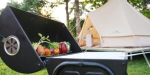 A luxurious, eco-friendly bell tent set up in a beautiful forest clearing at sunset.
