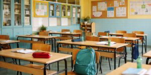 A school backpack on a wooden desk bathed in soft morning light representing academic pressure.