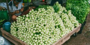 A lively outdoor farmers market scene featuring fresh produce under morning sunlight.