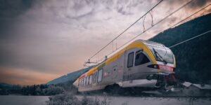 A sleek high-speed train traveling through a beautiful mountain landscape at sunset.