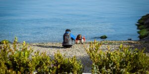 A parent and child looking into a reflective pool of water, symbolizing mirror neurons and emotional regulation.