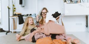 A parent and two children organizing clothes together in a bright, modern living room.