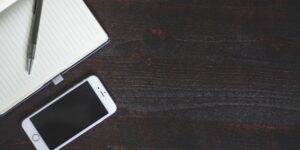 A clean wooden desk setup with analog planning tools and a smartphone placed face down.