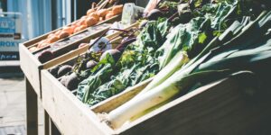 Fresh vegetables at a sunlit farmers market stall representing sustainable shopping.