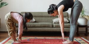 A parent and children stretching together in a sunny living room.