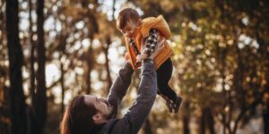 A parent and child observing nature together in a forest setting.