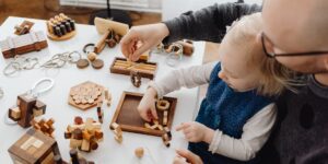 Parent and child working together on math puzzles at a wooden table.