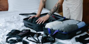 A neatly packed suitcase and travel essentials on a hotel bed.