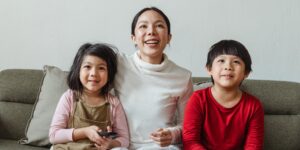 A family relaxing in a cozy living room watching a scenic nature documentary on a large screen.