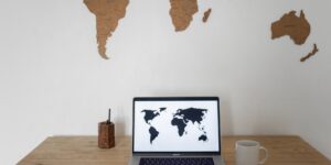 Home office desk with a laptop and world map background.