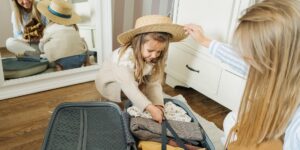 A travel bag packed for a family trip in a sunlit hotel room.