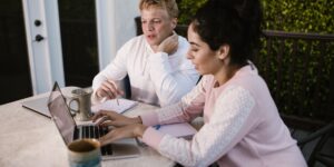 Two co-parents sitting at a table with notebooks, practicing calm communication.