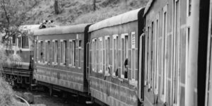 A scenic view of a coastal railway journey through a train window.