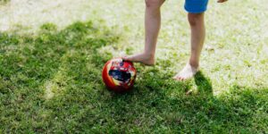 A child focused on a soccer ball on a field at sunset.