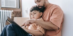 A parent and child sharing a calm, quiet moment reading together in a cozy bedroom.