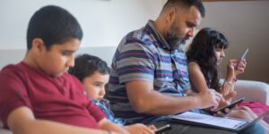 A parent cleaning a used tablet and smartphone to prepare them for a child's use.
