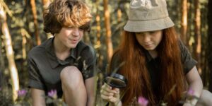 A child exploring nature with a magnifying glass in a sunny forest