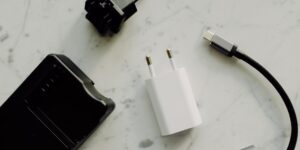 A professional flat-lay of universal travel adapters and charging cables on a wooden surface.