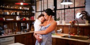 A calm, warm-toned kitchen scene at dusk showing a parent and child cooking together.