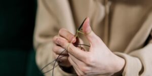 Close-up of hands mending a sweater to illustrate the slow-fashion repair movement.